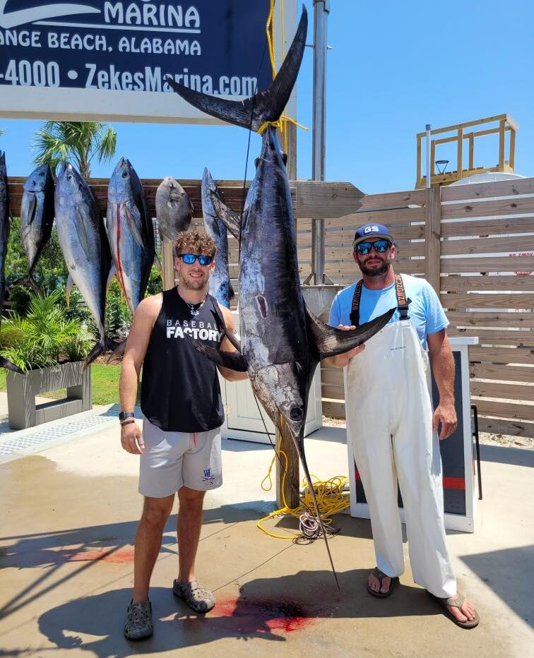 Trophy Marlin hanging up at dock with fisherman posing for photo